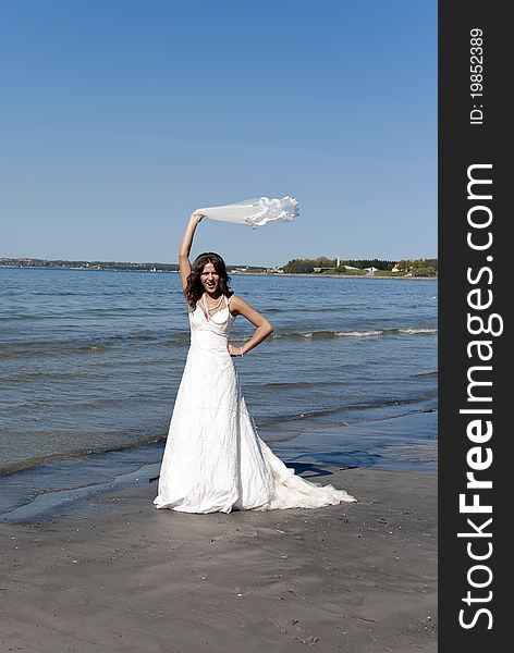 Beautiful young bride twirling overhead veil near the sea. Beautiful young bride twirling overhead veil near the sea