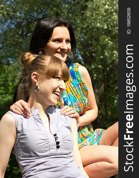 Two smiling girl-friends relaxing outdoor