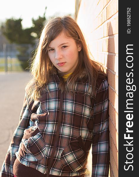 Portrait of a cute teenage girl leaning on a brick wall in the schoolyard. Portrait of a cute teenage girl leaning on a brick wall in the schoolyard