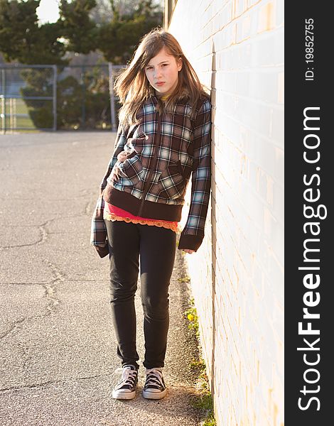 Portrait of a cute teenage girl leaning on a brick wall in the schoolyard. Portrait of a cute teenage girl leaning on a brick wall in the schoolyard