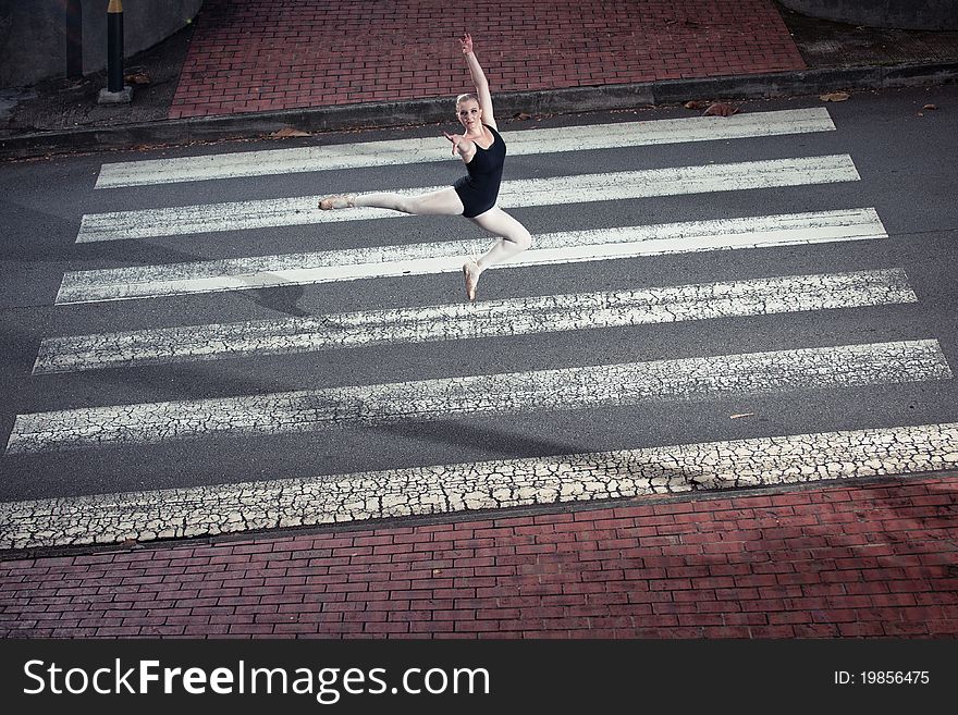 A Young Caucasian female ballerina dancing on a zebra crossing. A Young Caucasian female ballerina dancing on a zebra crossing