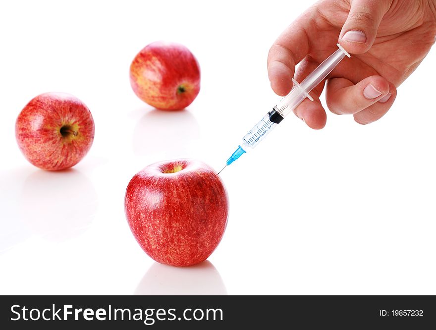 Closeup of a delicious, ripe red apple being injected by a medical syringe or hypodermic needle. Closeup of a delicious, ripe red apple being injected by a medical syringe or hypodermic needle.