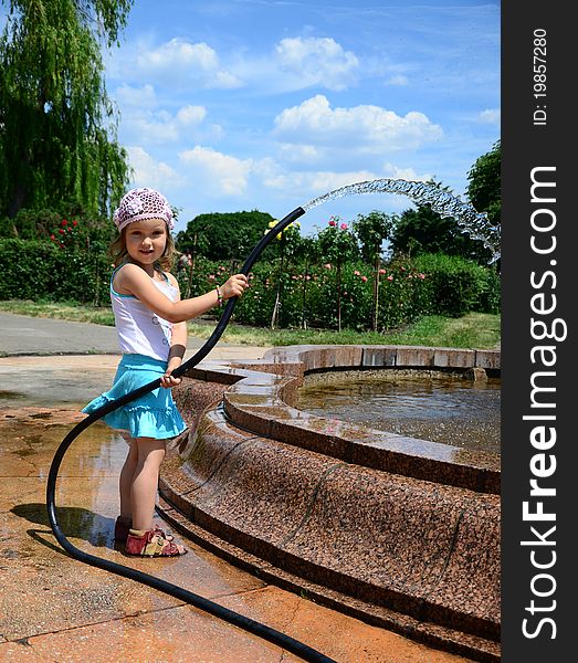Little girl with a hose near the fountain