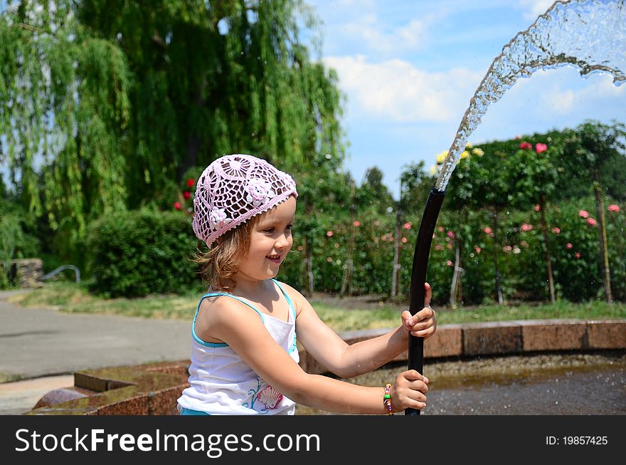Little girl with a hose near the fountain