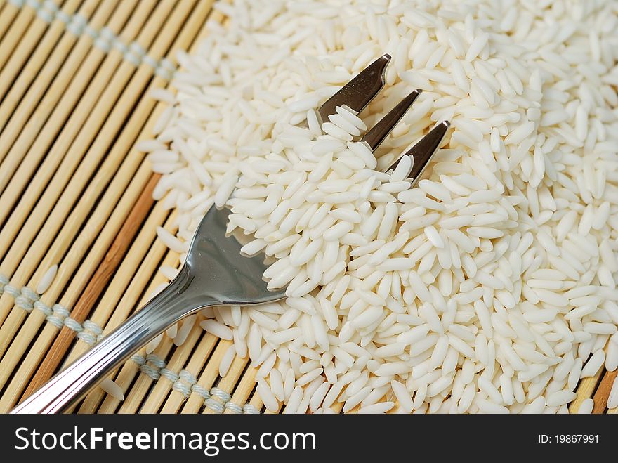 Fork in pile of freshly harvested white rice, staple diet in Asia. Fork in pile of freshly harvested white rice, staple diet in Asia.