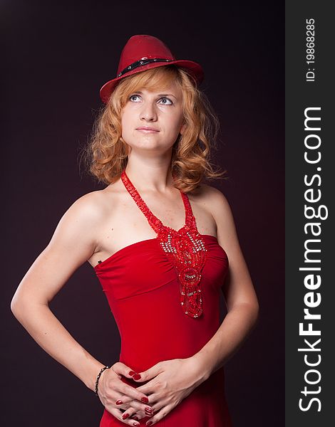 Red-haired girl in a red dress and red hat. Studio photography