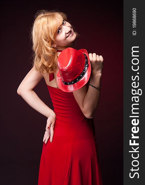 Red-haired girl in a red dress and red hat. Studio photography