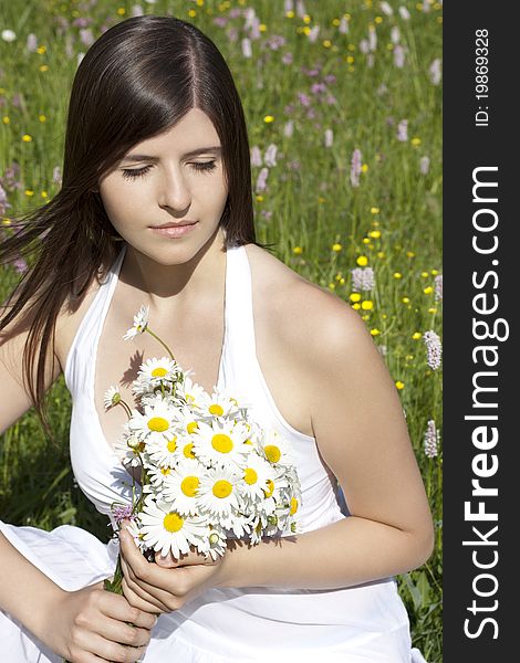 Portrait of a beautiful teenage girl holding ox-eye daisies and sunbathing in a flowery meadow. Portrait of a beautiful teenage girl holding ox-eye daisies and sunbathing in a flowery meadow