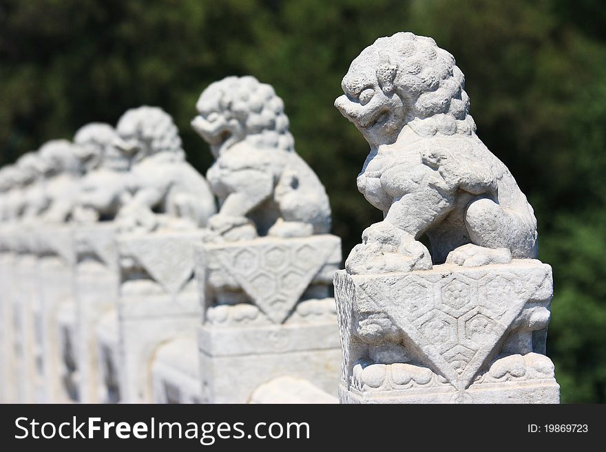 In the Summer Palace, these 544 carved white marble lions, in distinctive postures, sit at the column of the parapets on the 17-arch Bridge, which looks like a rainbow arching over the lake water.Beijing, China. In the Summer Palace, these 544 carved white marble lions, in distinctive postures, sit at the column of the parapets on the 17-arch Bridge, which looks like a rainbow arching over the lake water.Beijing, China