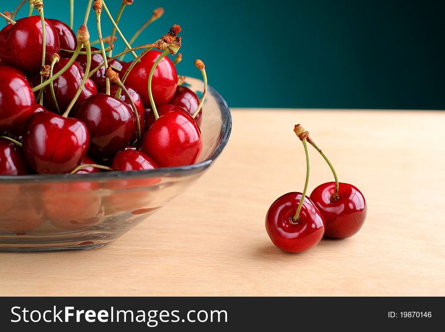 Cherries on glass container.Green gradient background.