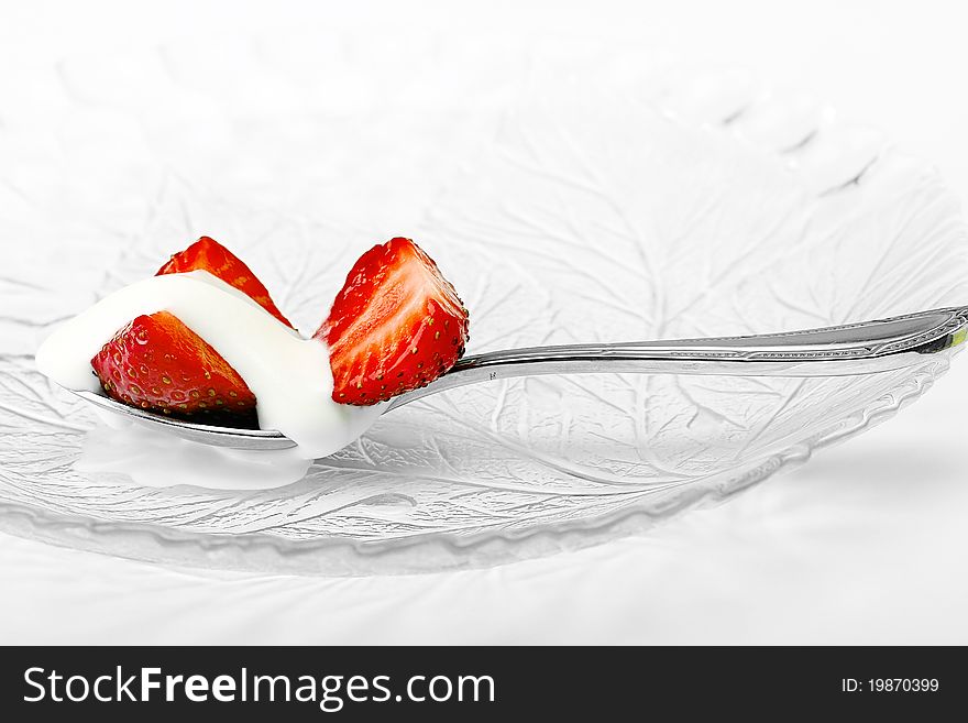 Red strawberry and white ice cream on spoon on white background