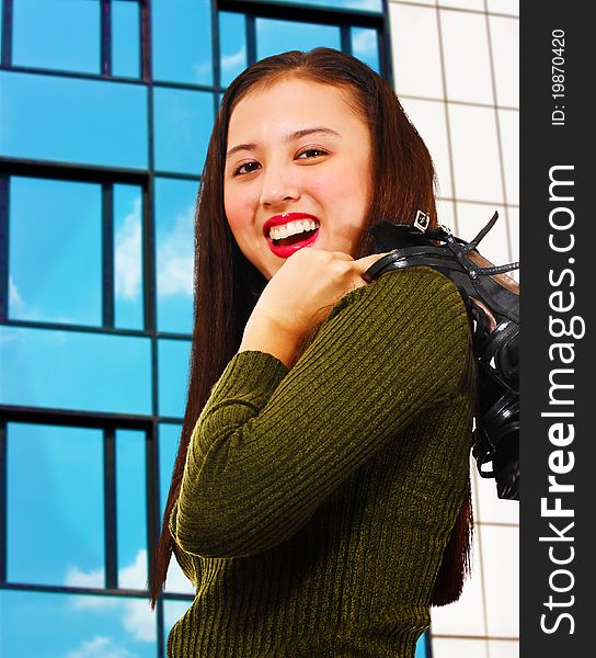 Attractive young woman smiling and standing in front of a reflective office building. Attractive young woman smiling and standing in front of a reflective office building