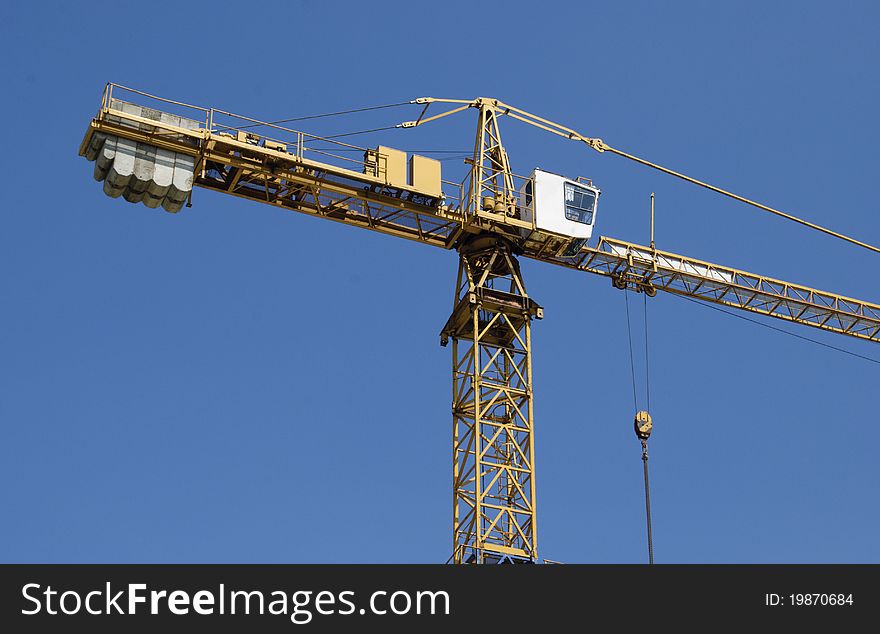 Hoisting crane on a background of blue sky