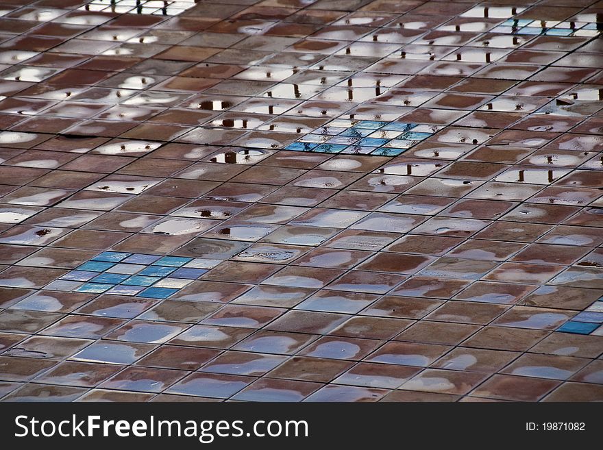 Puddles of water standing on a colorful tile walkway in Italy. Puddles of water standing on a colorful tile walkway in Italy