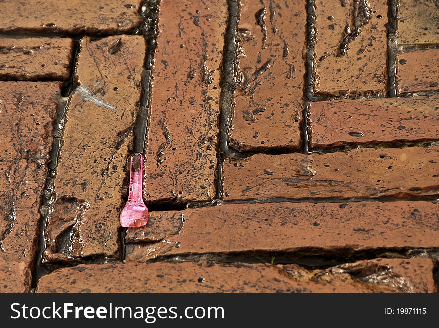 A plastic pink gelato spoon dropped on the brick pavement of the piaza in Siena, Italy. A plastic pink gelato spoon dropped on the brick pavement of the piaza in Siena, Italy