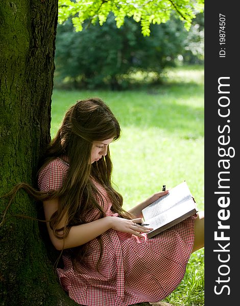 Attractive girl with long hair is studying in the park. Attractive girl with long hair is studying in the park