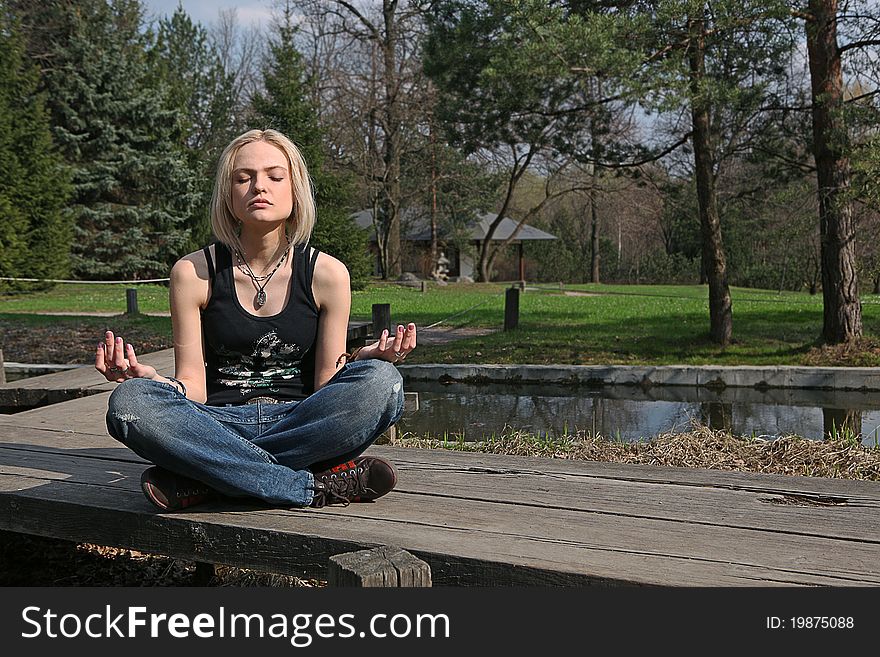 Pretty blond girl, meditating at Japanese garden. Pretty blond girl, meditating at Japanese garden