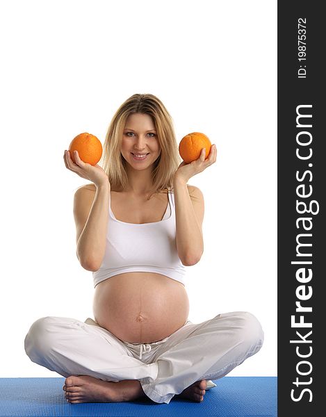 Pregnant Woman Practicing Yoga And Keeps Oranges