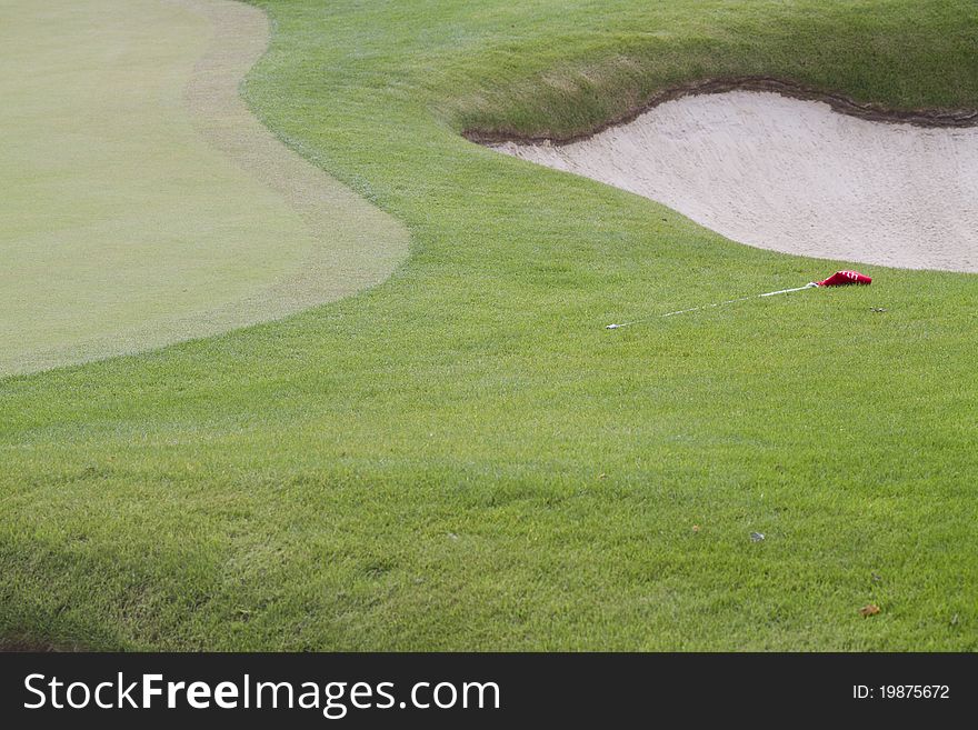 Golf course bunker green and a red flag