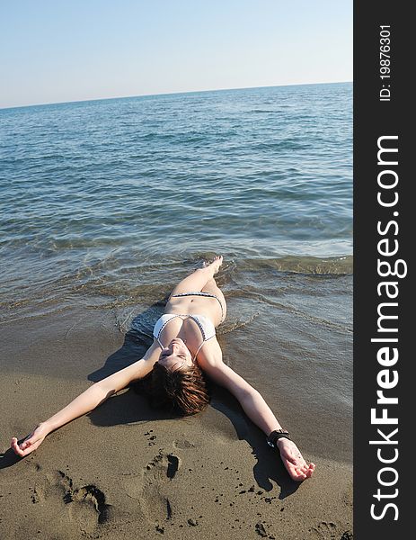 Happy young woman relax on beautiful beach at fresh summer morning and enjoy first ray of sun. Happy young woman relax on beautiful beach at fresh summer morning and enjoy first ray of sun