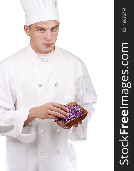The young chef in uniform and chef's hat in his hands chopped red cabbage.