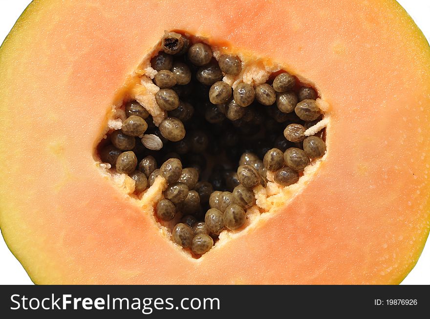 Close up of a papaya cut in half with black seeds and white background