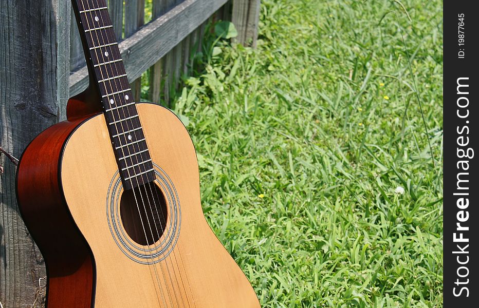 Acoustic guitar leaning on wooden fence. Acoustic guitar leaning on wooden fence.