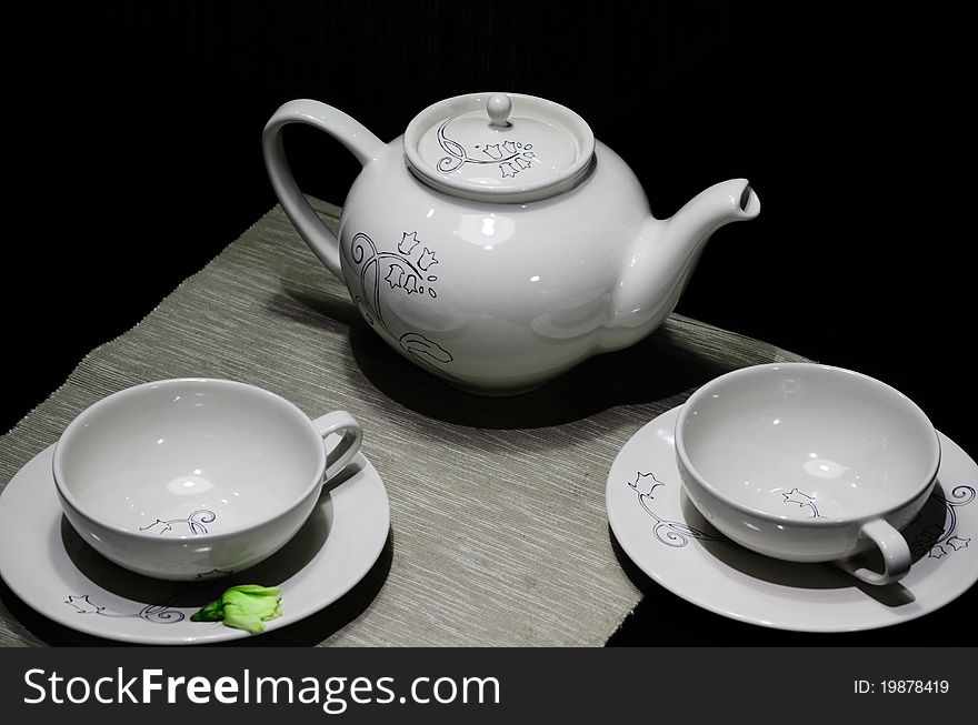 A teapot and two teacups are shot against black backgrounds. Ordinary and mysterious. A teapot and two teacups are shot against black backgrounds. Ordinary and mysterious.