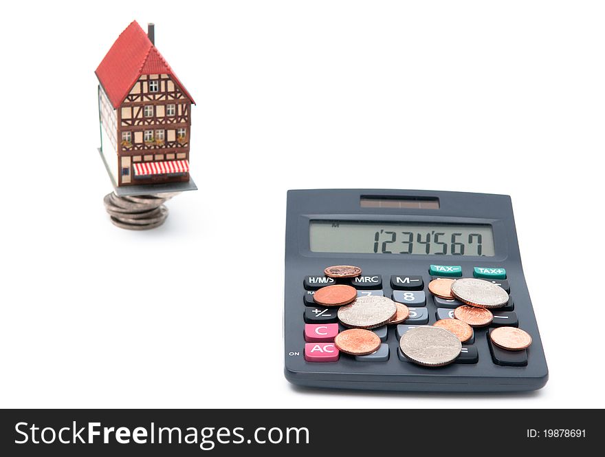 The photo of house with coins and calculator over white background