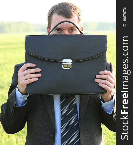 Businessman closes black briefcase in the field