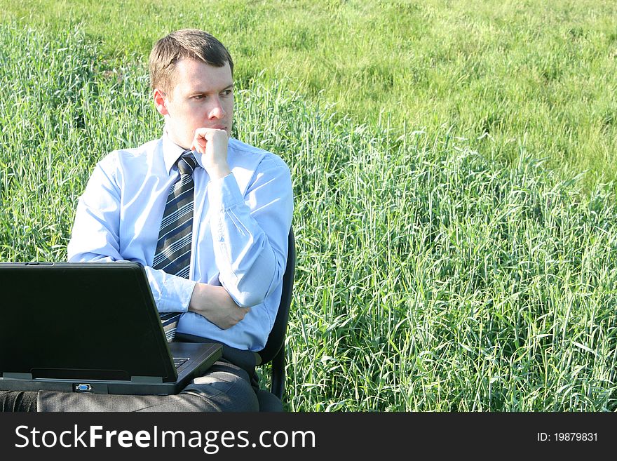 Pensive businessman in the field with laptop. Pensive businessman in the field with laptop