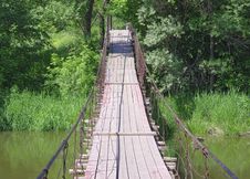 Old Suspension Walk Bridge Across River In Forest Stock Photo