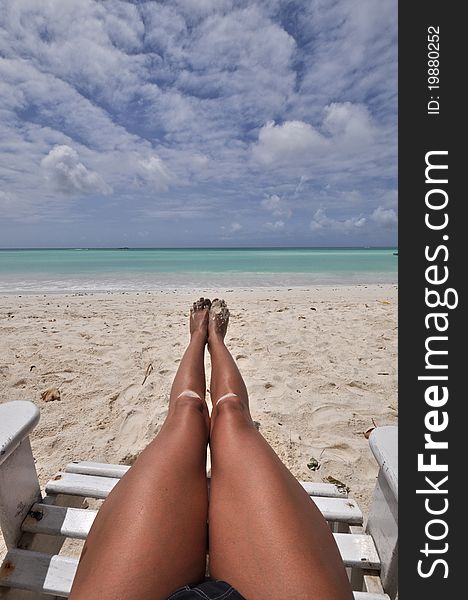 Long legs of woman on beach chair on white sand. Long legs of woman on beach chair on white sand