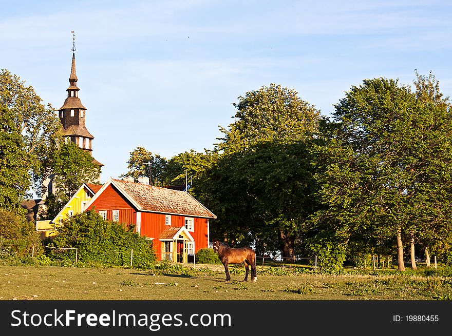 Red and yellow house, with a church behind and a horse in front. Red and yellow house, with a church behind and a horse in front.