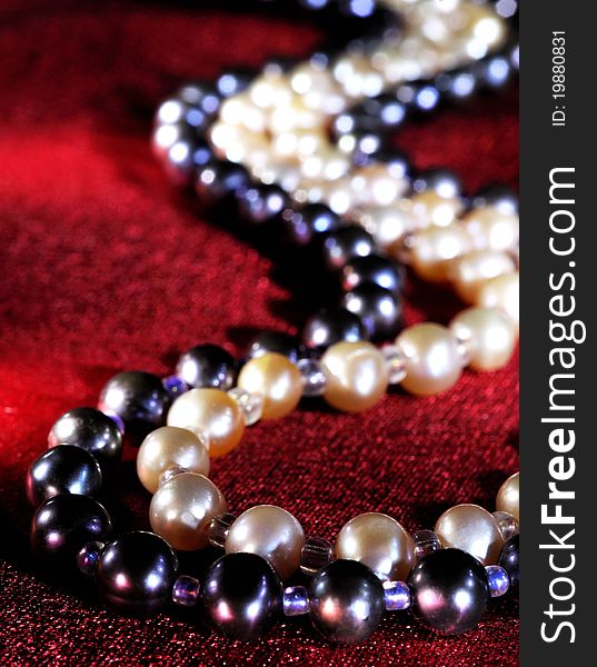 White and black Pearl necklace on a red silk, close up
