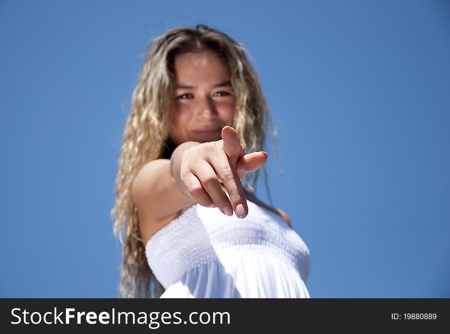 Portrait of the young woman pointing a finger against the blue sky. Portrait of the young woman pointing a finger against the blue sky