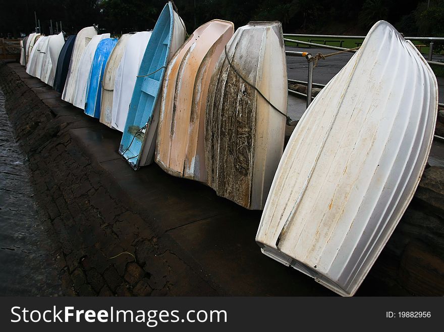 Row of dinghy rowboats leaning against a rail. Row of dinghy rowboats leaning against a rail.