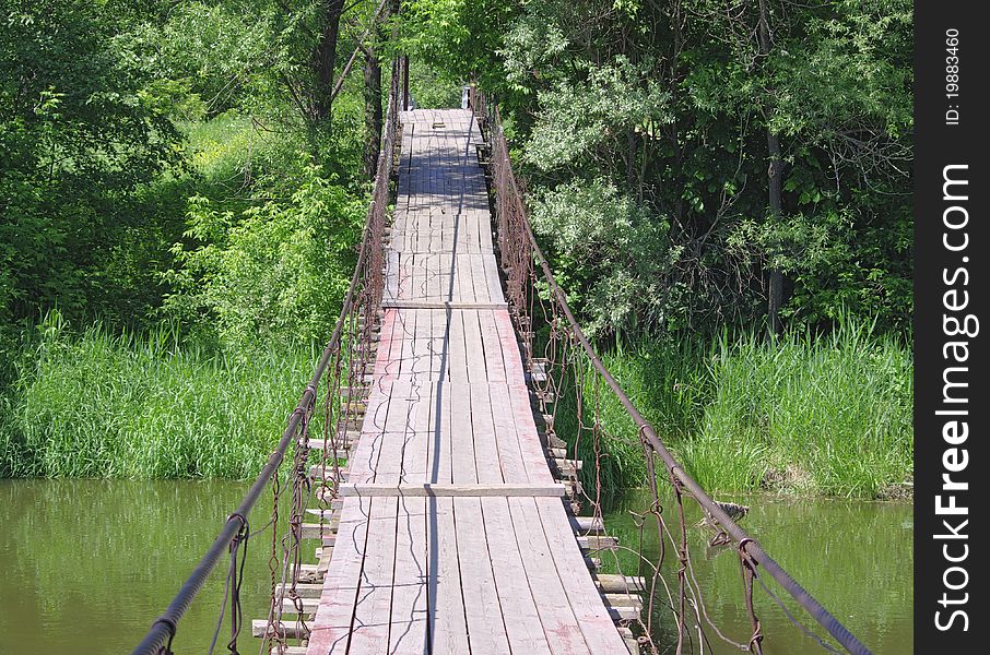 Old Suspension Walk Bridge Across River In Forest