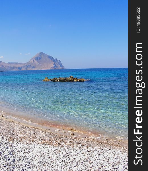 Beautiful pebble beach with crystal-clear waters and view of the mountain