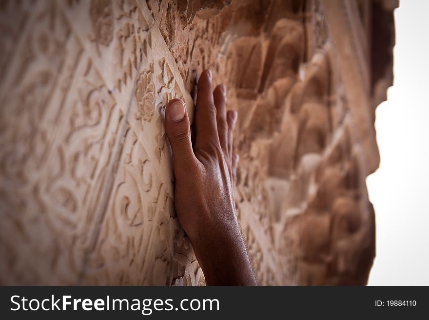 A hand reaching up to touch carvings. A hand reaching up to touch carvings