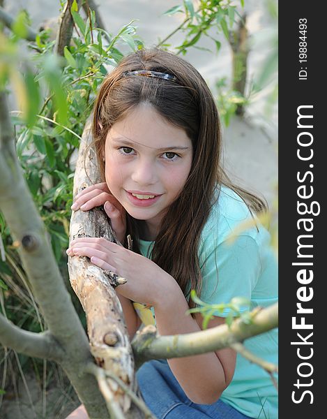 Young girl posing at a tree wearing a green shirt