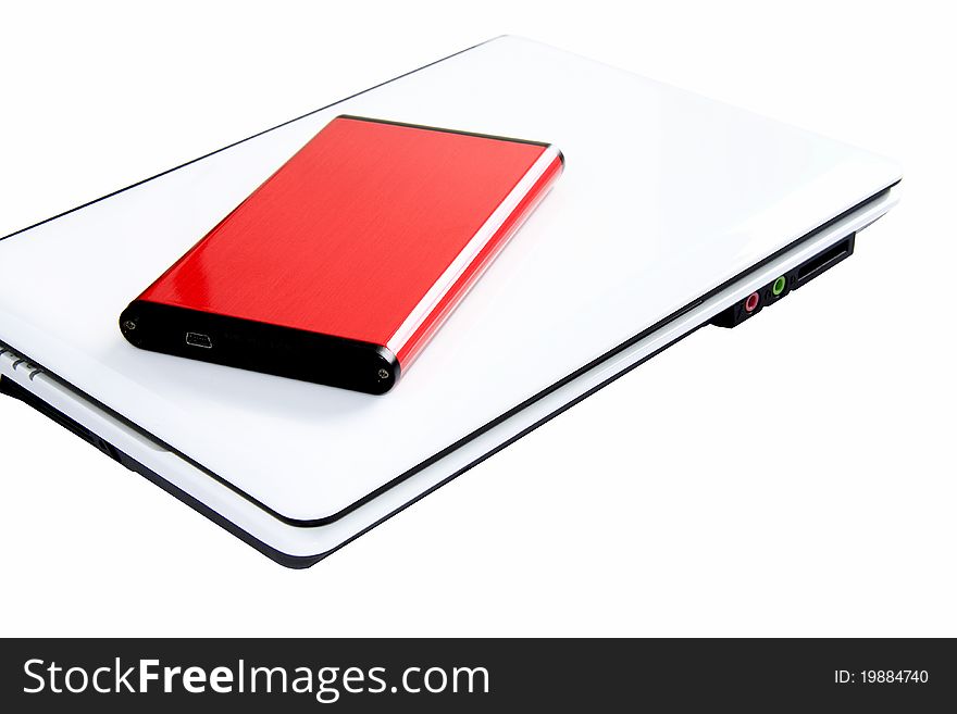 Portable red external hard disk for extra data or file storage, on top of white laptop computer with white background. Portable red external hard disk for extra data or file storage, on top of white laptop computer with white background.