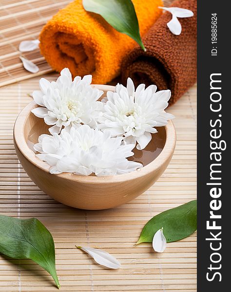 Towels and white daisies in wooden bowl. Spa and body care. Towels and white daisies in wooden bowl. Spa and body care
