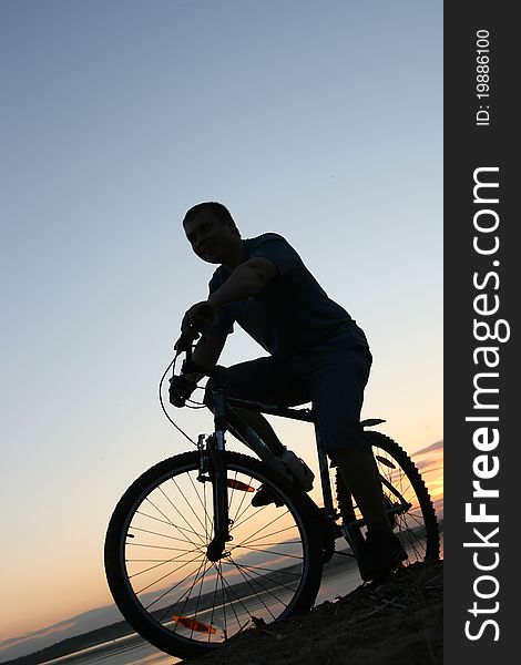 Silhouette of a cyclist riding along the beach