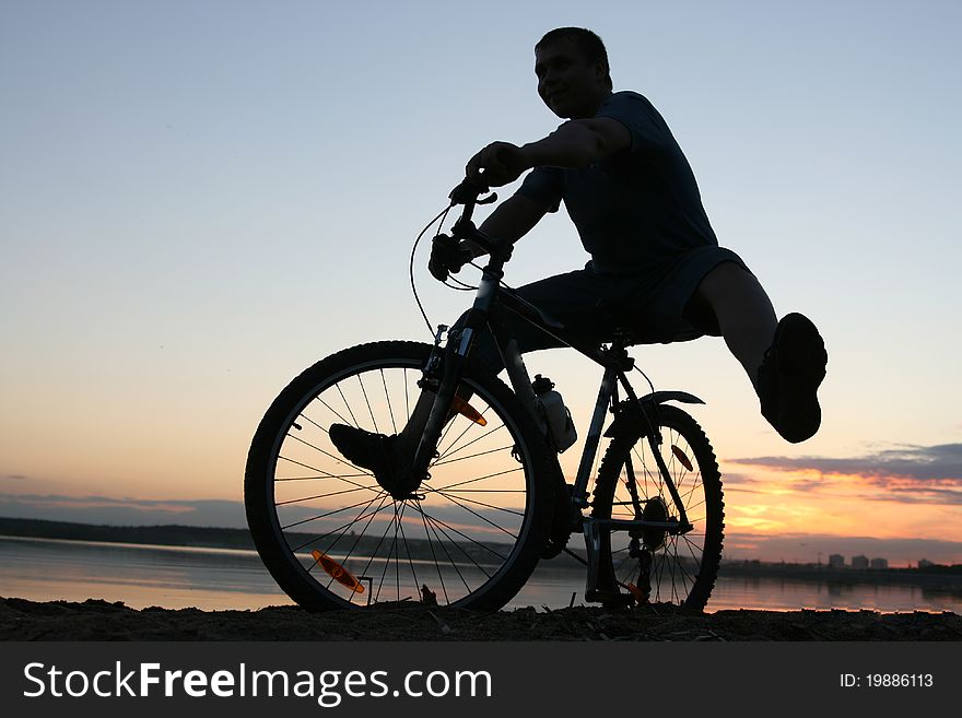 Silhouette of a cyclist riding along the beach