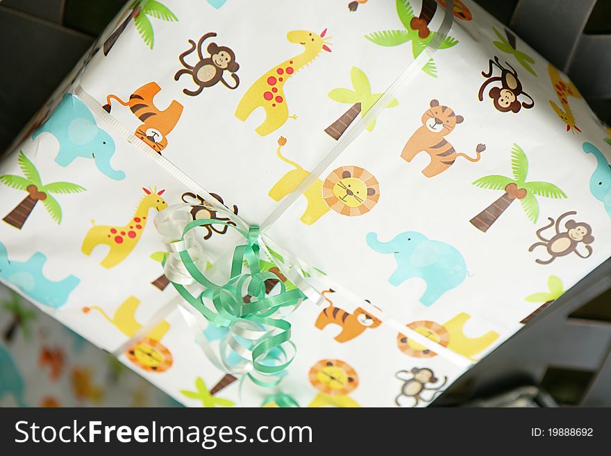 This a picture of a gift, wrapped in a children's gift warp paper. With a light blue ribbon. Picture of Lions, Palm Tress and little monkey's on the paper. This a picture of a gift, wrapped in a children's gift warp paper. With a light blue ribbon. Picture of Lions, Palm Tress and little monkey's on the paper.
