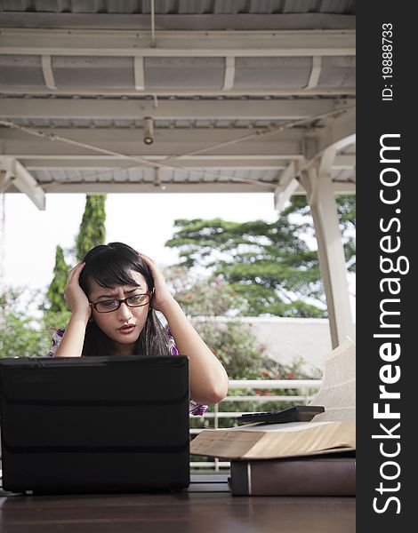Stressed asian woman with her laptop and book. Stressed asian woman with her laptop and book