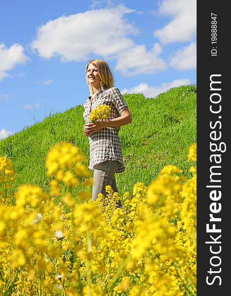 Young smiling girl in the summer field full of yellow flowers. Young smiling girl in the summer field full of yellow flowers