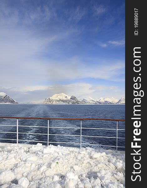 The mountainous, snow covered, Norwegian Coastline from the snowy deck of a cruise liner. The mountainous, snow covered, Norwegian Coastline from the snowy deck of a cruise liner