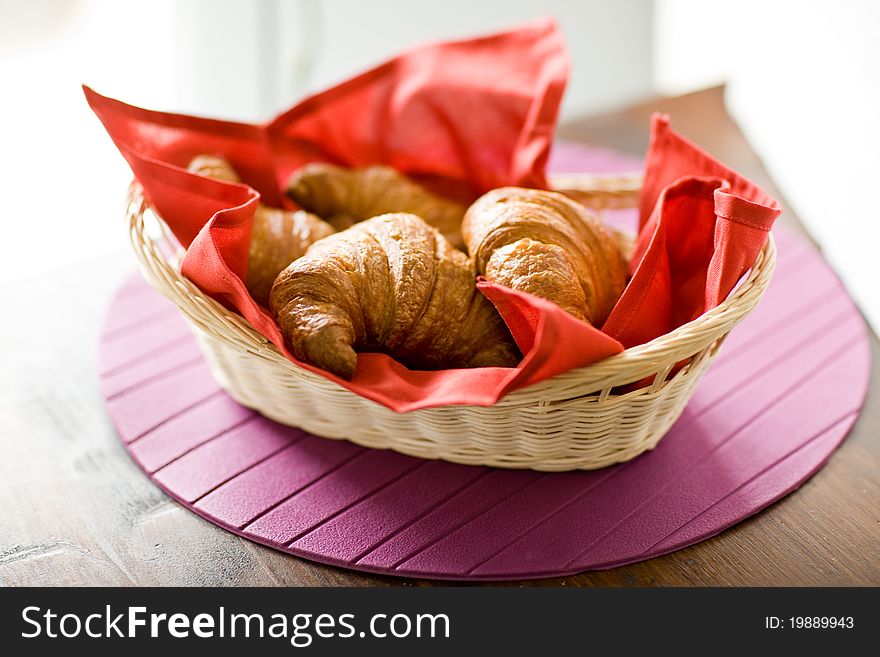 Photo of delicious warm and fresh croissants on wooden table by daylight